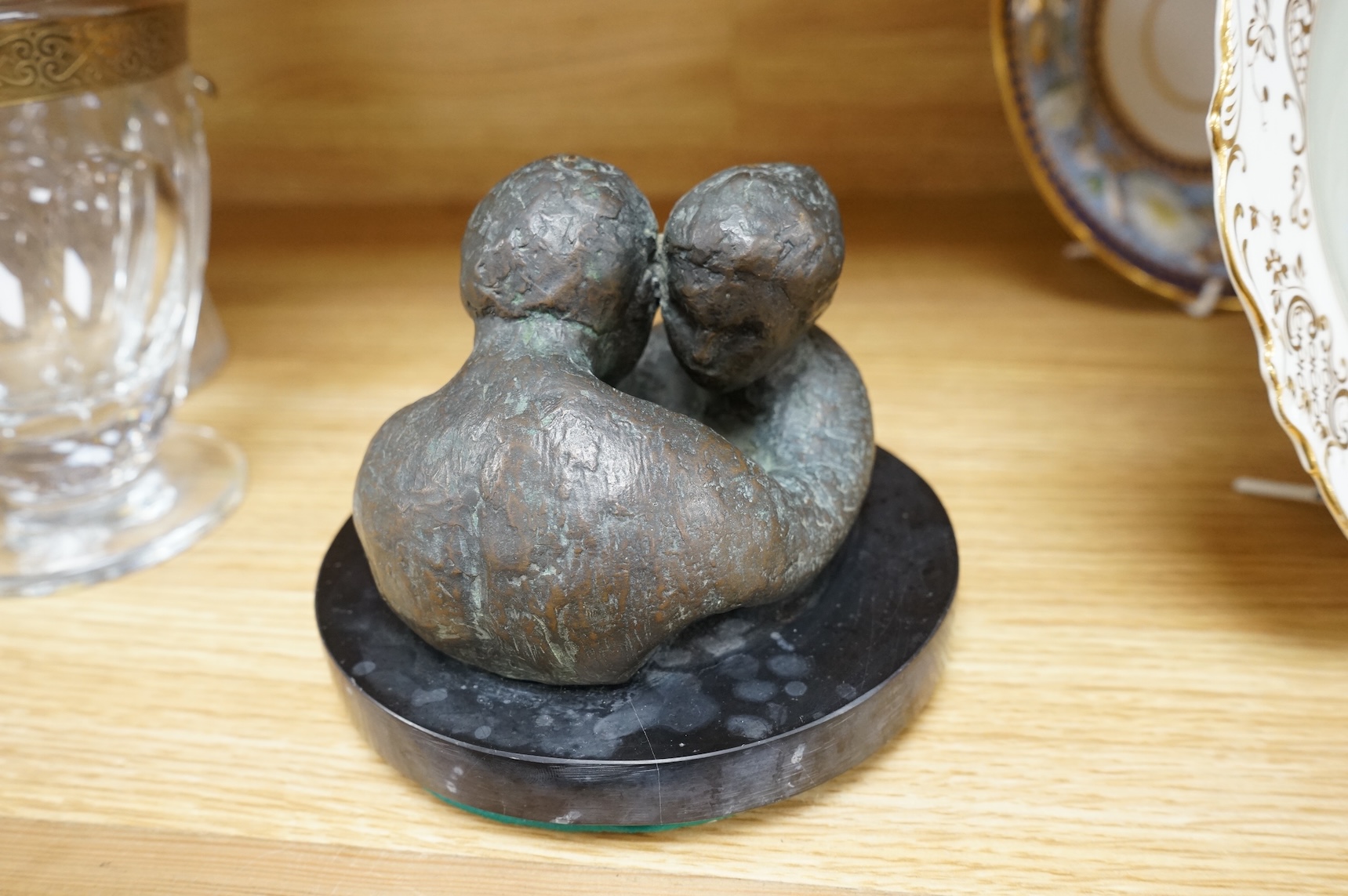 A contemporary bronze revolving sculpture of an embracing couple, unsigned, 16cm in diameter